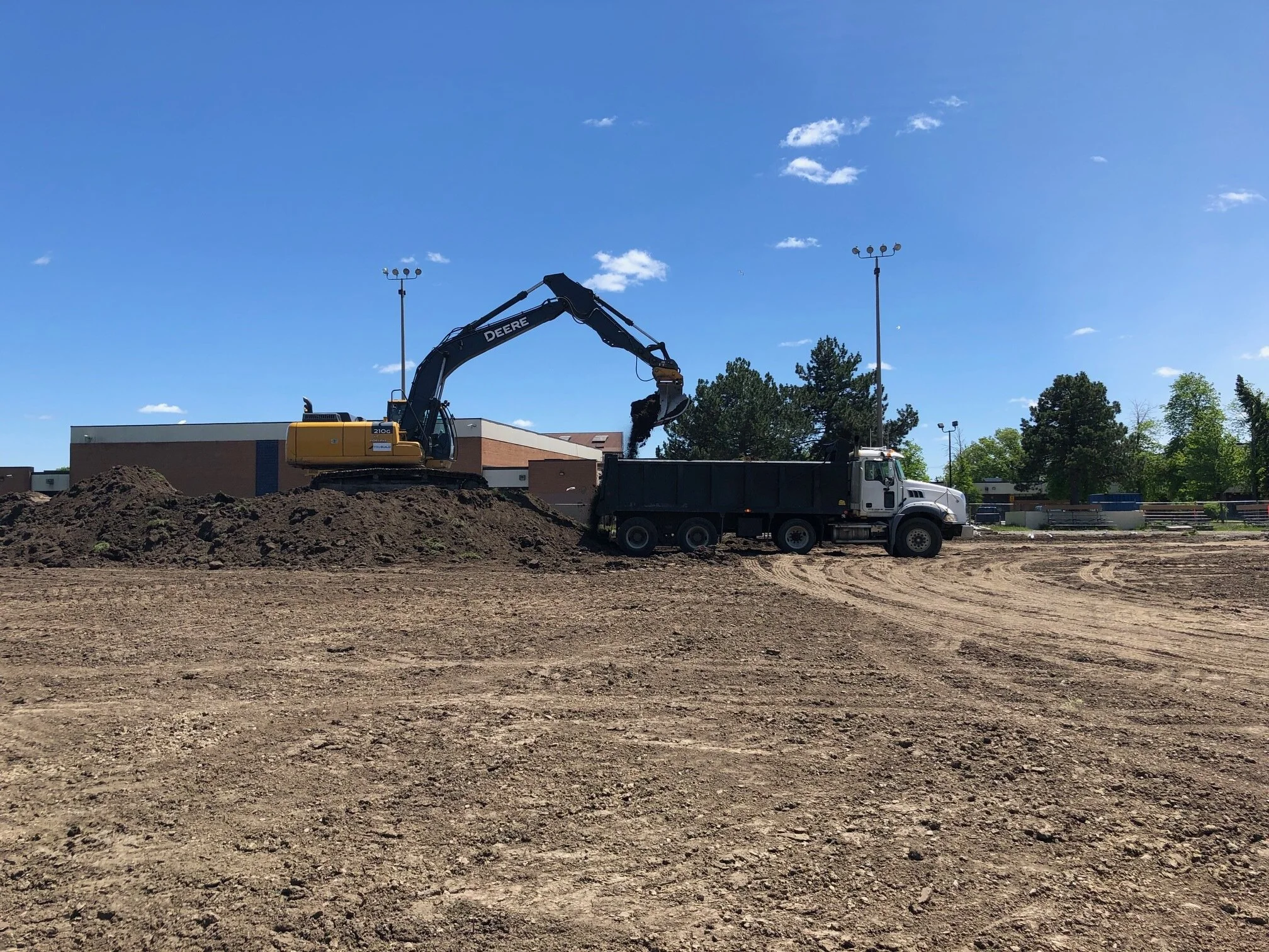 Excavator loading dump truck on graded site